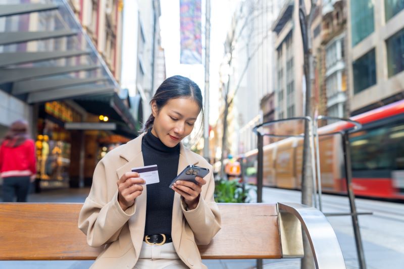 Woman in citiy paying on phone with card